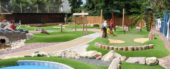 Adventure-Golf-Anlage mit bunten Figuren, Spielstationen, künstlichem Rasen und Felsen
